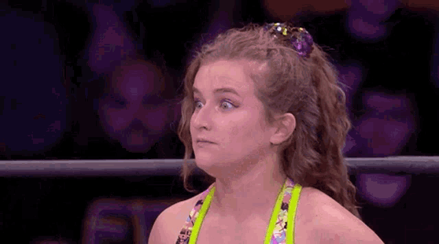 a woman is standing in a wrestling ring with a ponytail and making a funny face .