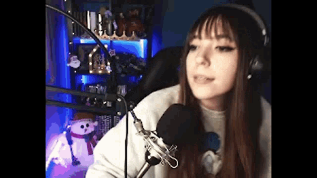 a girl wearing headphones is talking into a microphone in a room .
