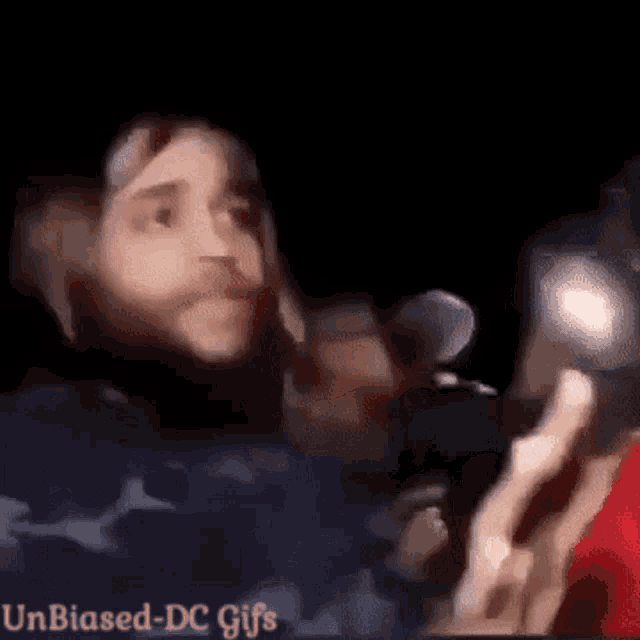 a man with a beard is holding a microphone in his hand .
