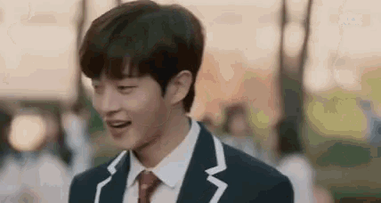 a young man in a suit and tie is smiling in a park .