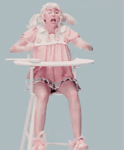 a woman in a pink dress sits in a high chair