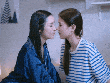 two women kissing each other with one wearing a blue and white striped shirt