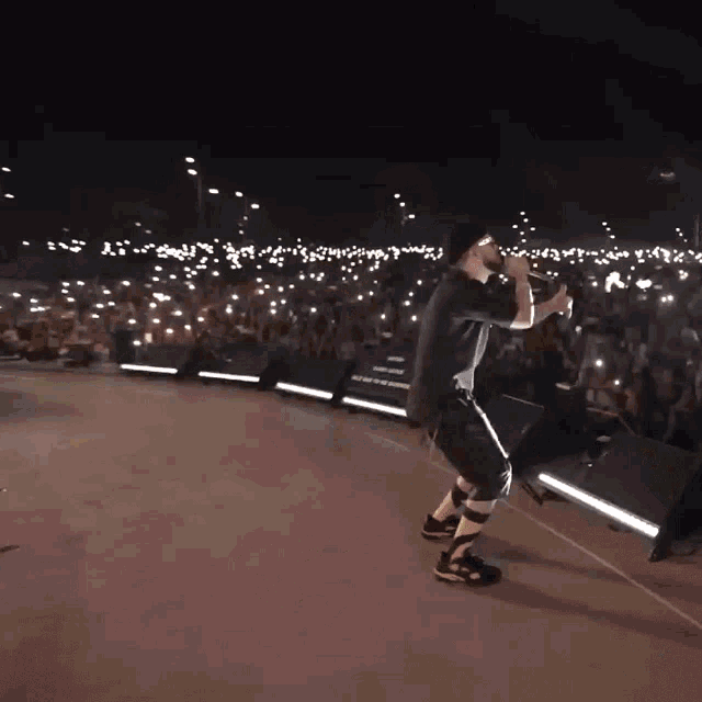 a man singing into a microphone in front of a crowd that is lit up