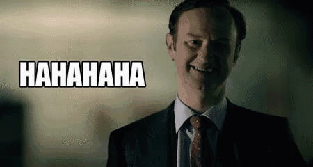 a man in a suit and tie is smiling and laughing with the words `` hahahaha '' behind him .