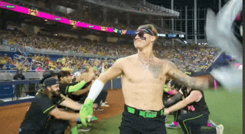 a man without a shirt is on a baseball field surrounded by fans
