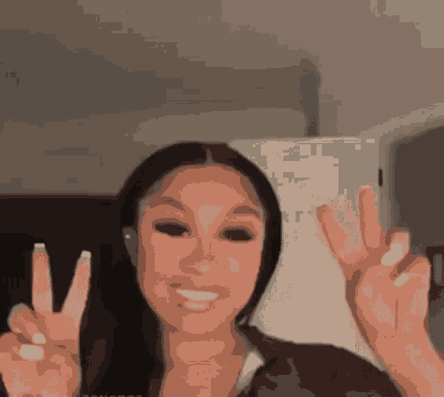 a woman is giving a peace sign with both hands .