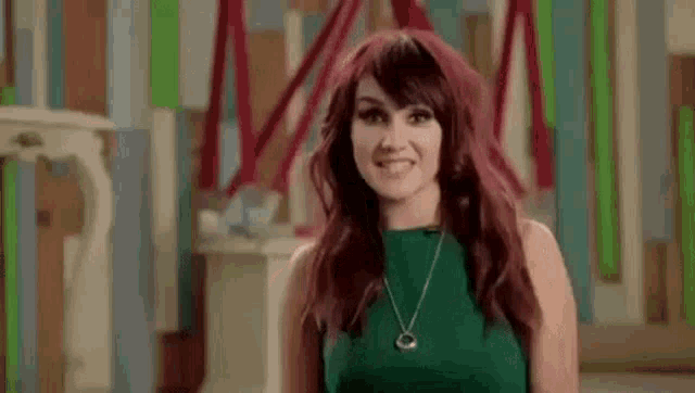 the woman is wearing a green dress and a necklace and smiling .