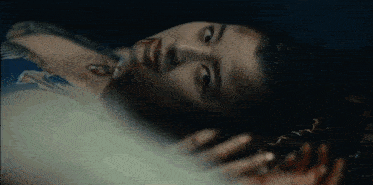 a woman is laying on the floor with blood on her face and a tattoo on her chest .