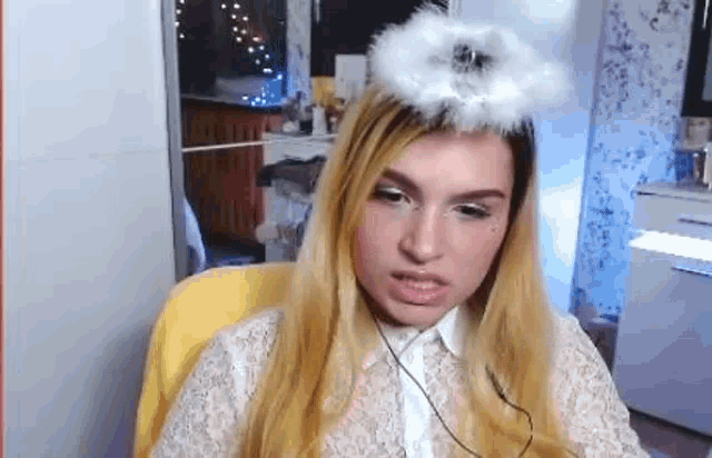 a woman is sitting in a chair wearing a white angel wing on her head .