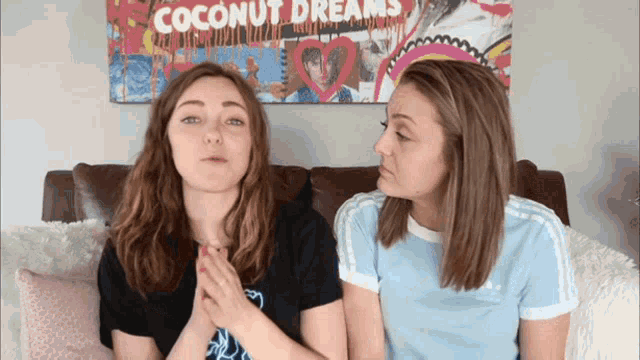 two girls sitting on a couch in front of a coconut dreams poster