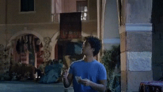 a man in a blue shirt is walking down a street holding a piece of paper .