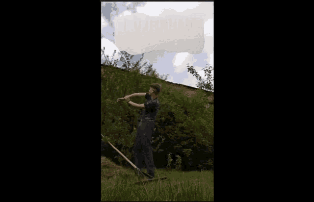 a man is standing in the grass with a rake in his hand
