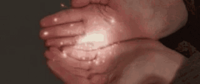 a person is holding something in their hands that is glowing in the dark .