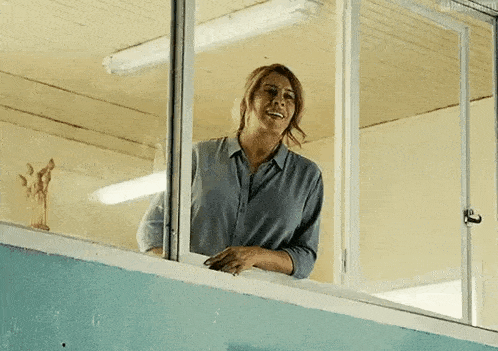 a woman is standing on a balcony looking out a window .