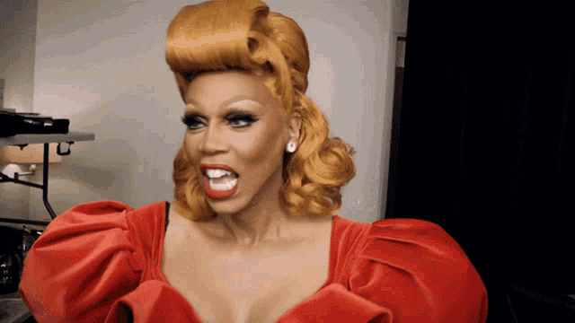 a drag queen wearing a red dress and earrings makes a funny face