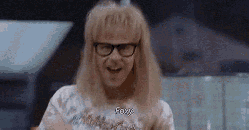 a man wearing glasses and a tie dye shirt is talking to a woman .