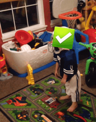 a child in a little tikes helmet stands in a play room