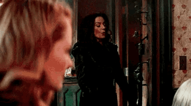 two women are standing next to each other in a room .