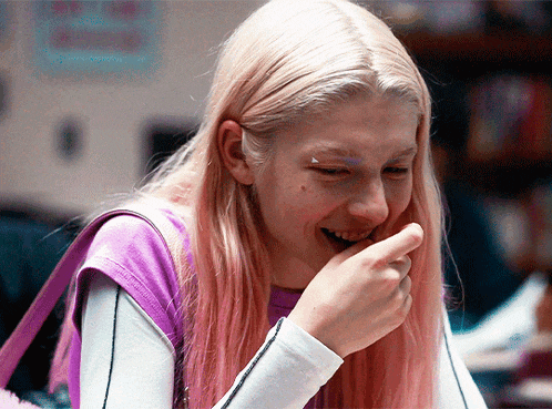 a girl with pink hair is laughing and covering her mouth