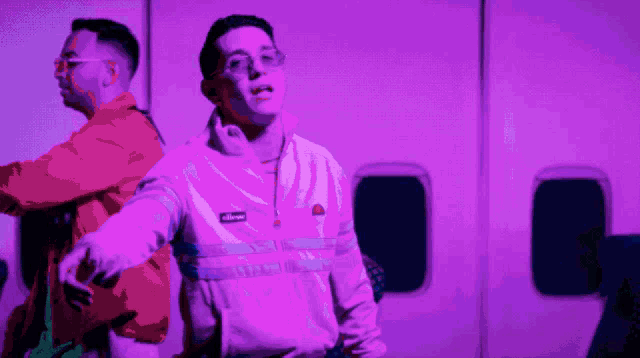 a man in an ellesse jacket stands next to another man in an orange jacket