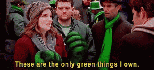 a group of people are standing in a crowd wearing green clothes and scarves .