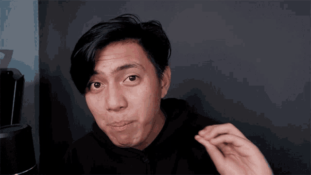 a man in a black hoodie is making a silly face