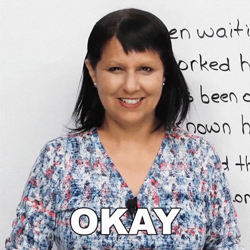 a woman stands in front of a white board with the words okay written on it