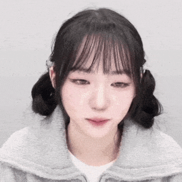 a girl with pigtails and bangs is wearing a grey jacket and a white shirt