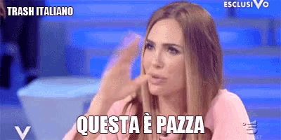 a woman is sitting in front of a blue background and says trash italiano questa e pazza .