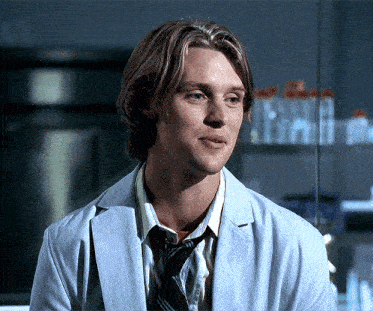 a man in a lab coat and tie is smiling and looking at the camera