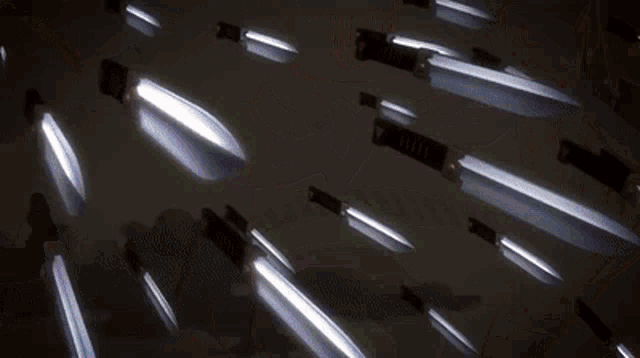 a bunch of knives are laying on a table with a light coming out of them