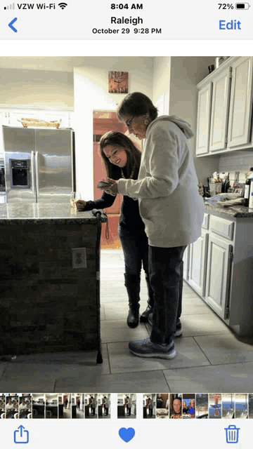 a phone screen shows a photo of two women in a kitchen