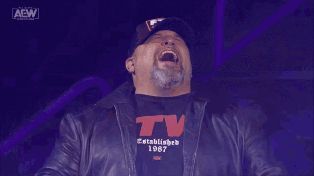 a man wearing a shirt that says tv established 1987 is laughing