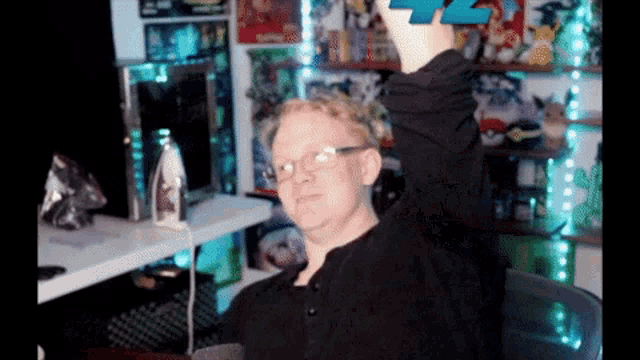 a man wearing glasses is holding up a game controller with the number 42 on it