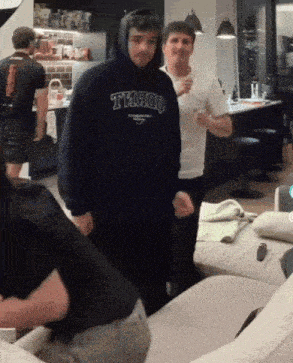 a man wearing a hoodie that says t1900 stands in a room