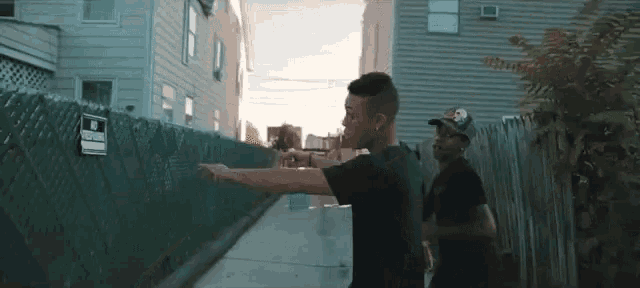 two men are standing next to each other on a sidewalk .