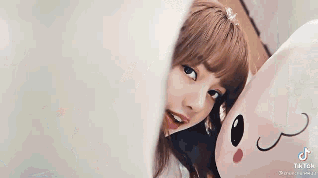 a girl is standing next to a stuffed animal and smiling .