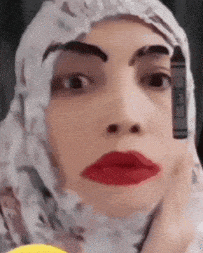 a woman is wearing a hijab and has a crayon on her eyebrow .