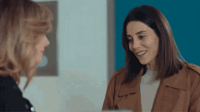 two women are talking to each other and one is wearing a brown coat