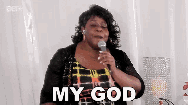 a woman singing into a microphone with the words my god on her face