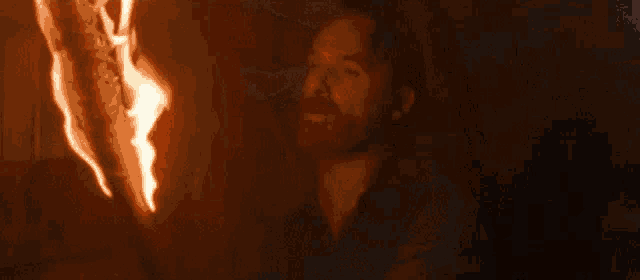 a person is standing in front of a fire in the dark .