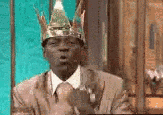 a man in a suit and tie wearing a gold crown