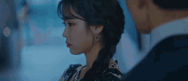 a man and a woman are standing next to each other and looking at each other . the woman is wearing earrings .