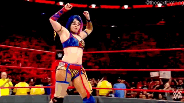 a woman in a wrestling ring with her arms in the air