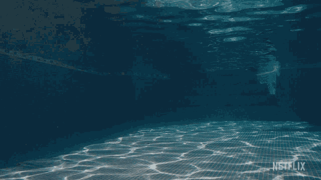 a person is swimming underwater in a pool with netflix on the bottom