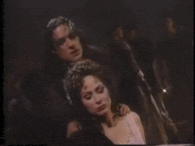 a man is holding a woman 's neck in a dark room in a movie .
