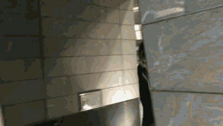 a person is walking down a hallway with a reflection of a person in the wall