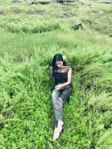 a woman in a black dress is laying on the grass