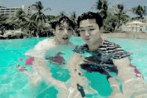 two men are standing in a swimming pool with a palm tree in the background
