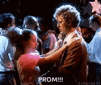 a man and a woman are dancing at a prom in front of a crowd of people .